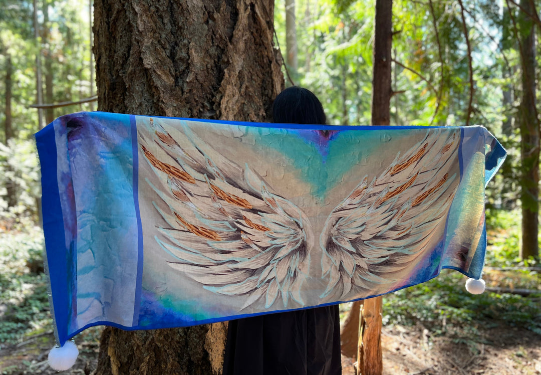 Person holding a fabric with angel wings design in a forest setting